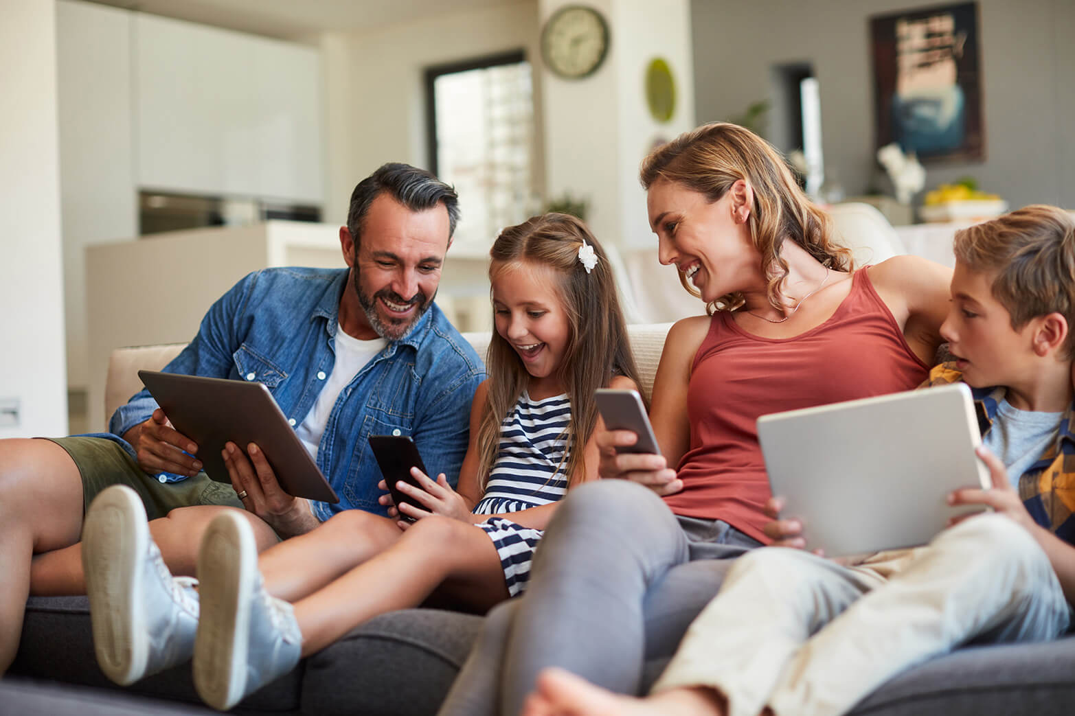 Family sitting on the couch together on their devices