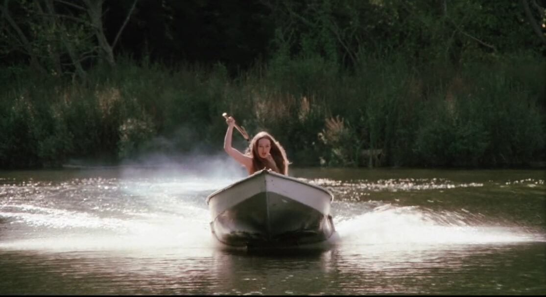 A woman holding an axe speeds toward an unseen victim in a motorboat. I Spit on Your Grave is one of the nastiest movies on Tubi.