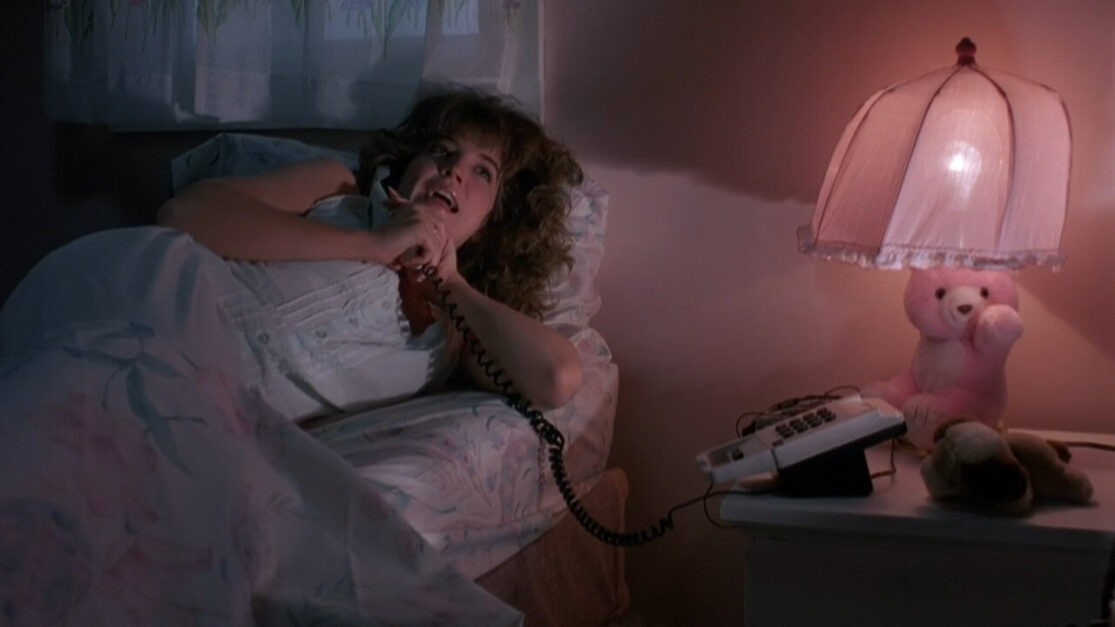 A teenage girl talks on the phone while lying in bed.