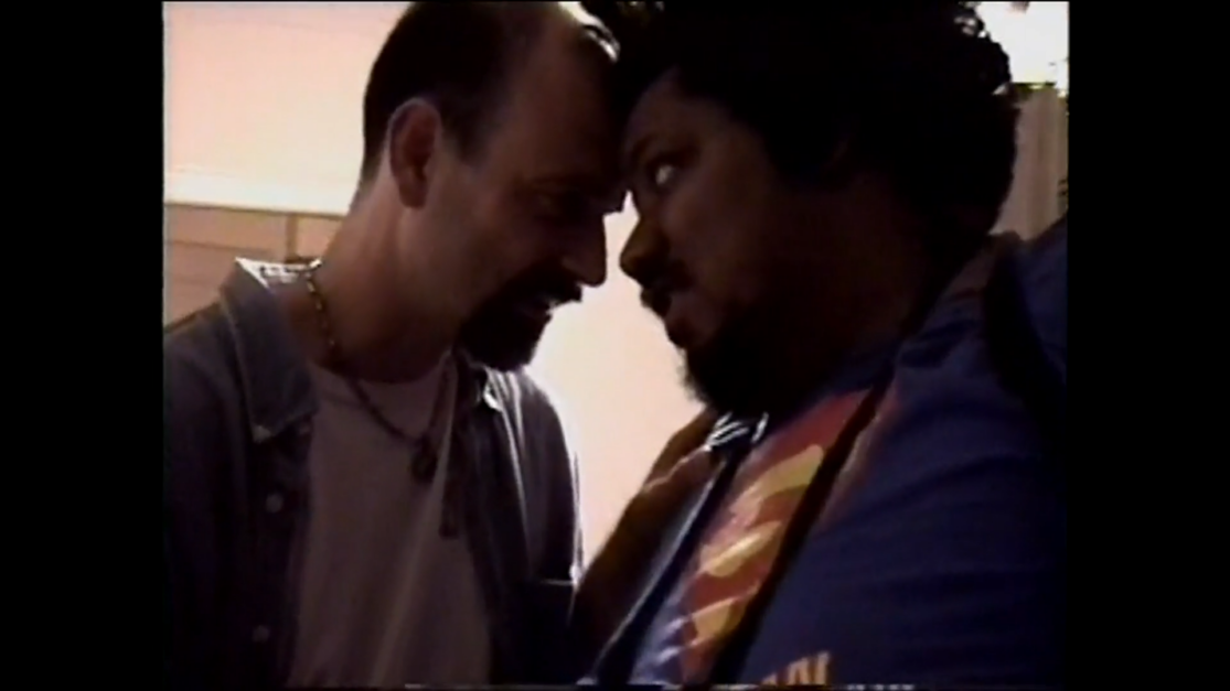 Two men, one white and one black, touch foreheads.