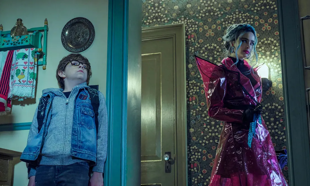 A small boy hides from a menacing woman wearing a spiky red raincoat.