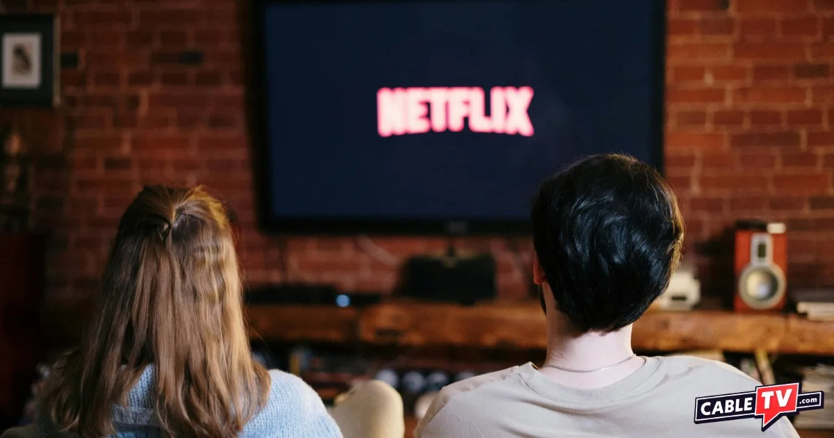 Woman and man sitting side by side looking at a TV screen with Netflix logo